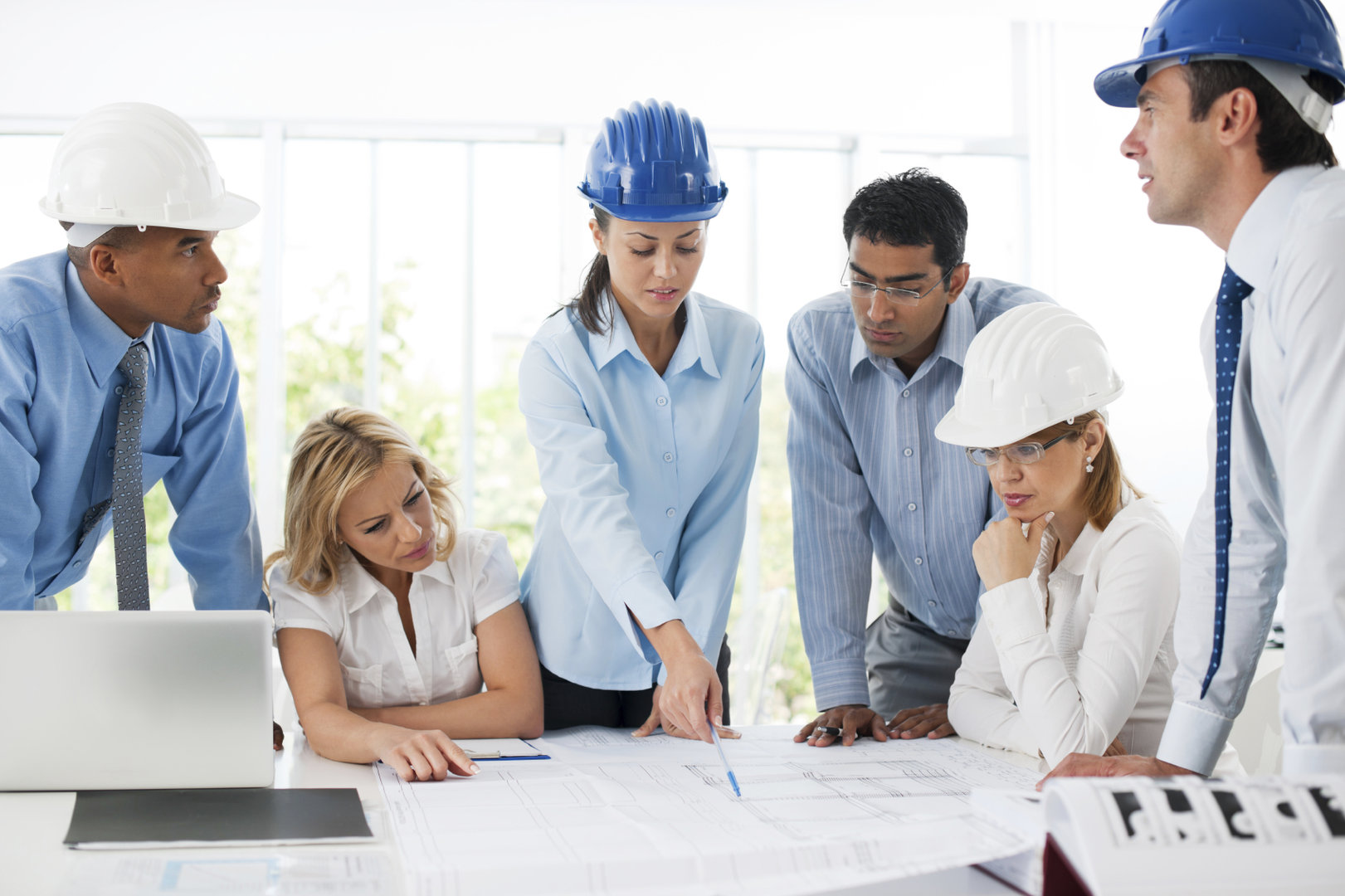 Six construction employees looking at blueprints