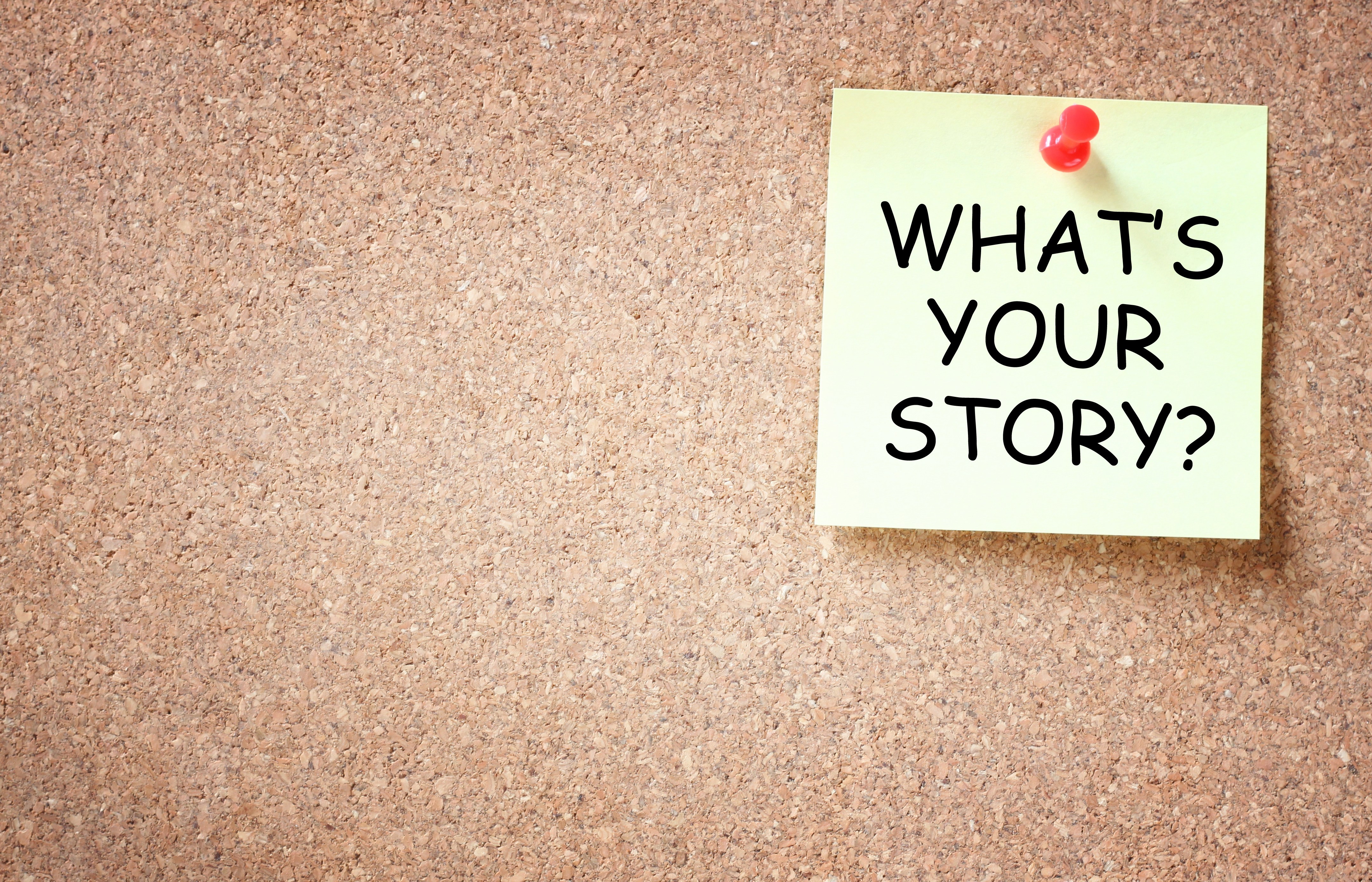 A cork board with a post-it tacked to it that says “What’s your story?”